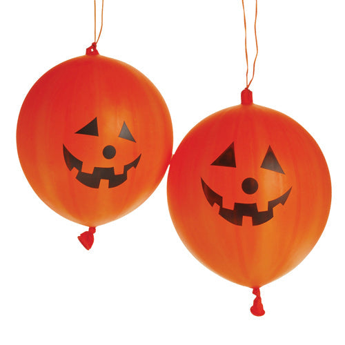 Orange jack-o-lantern rubber punch balls with elastic handles, used as prizes at a school Halloween carnival